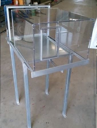 Una caja de acrílico transparente está colocada encima de una mesa de metal.