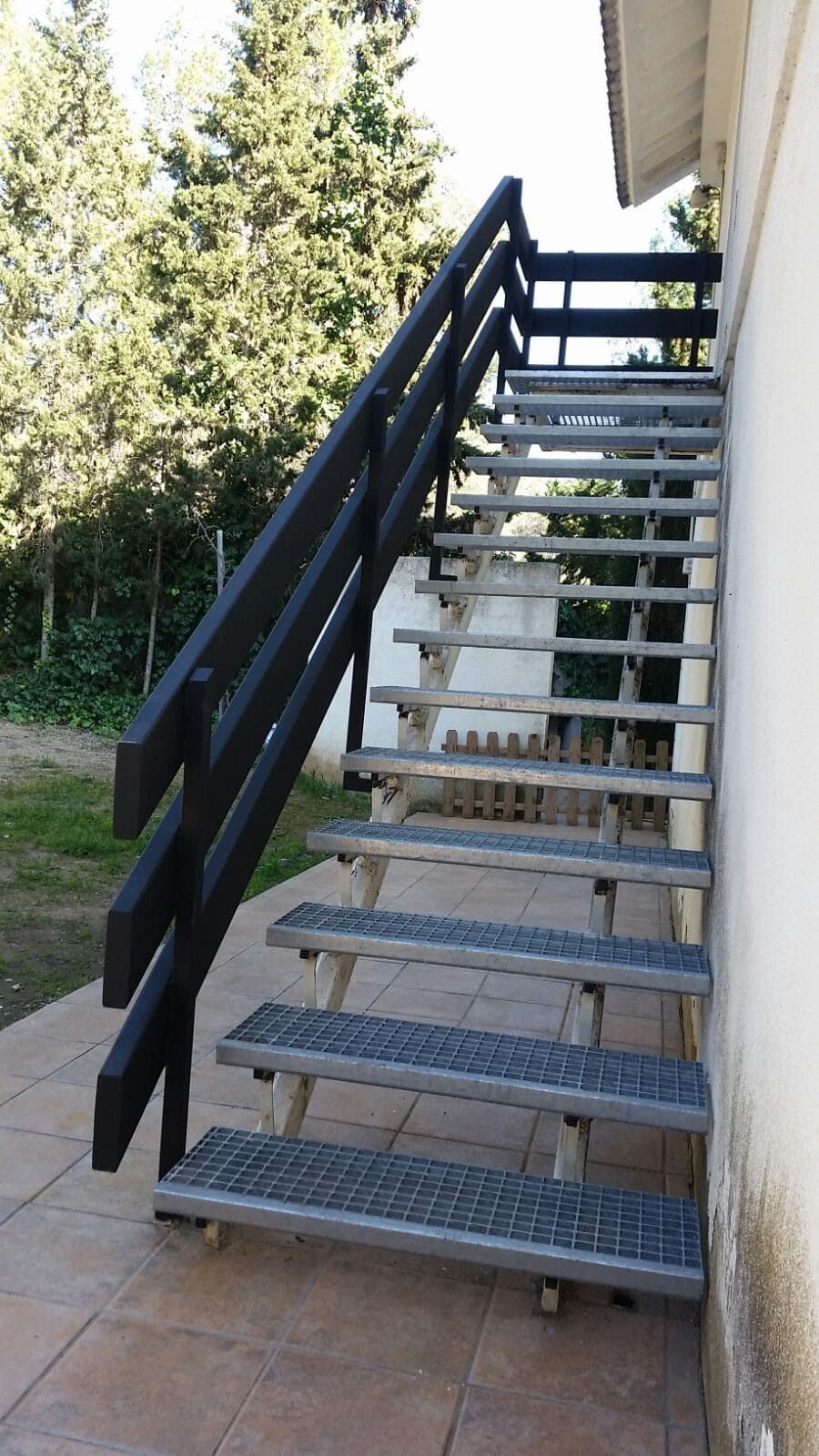 Un conjunto de escaleras con una barandilla negra en el costado de un edificio.