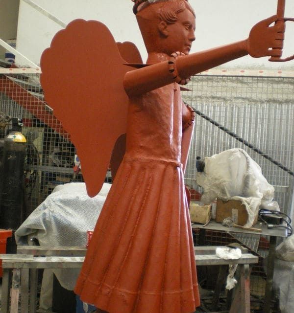 Una estatua de una mujer con alas de ángel sosteniendo una vela.