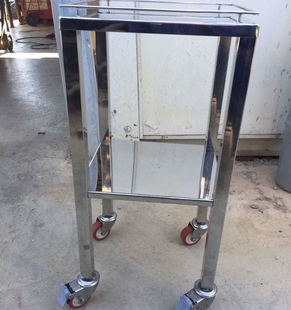 Un pequeño carrito de acero inoxidable con ruedas rojas.