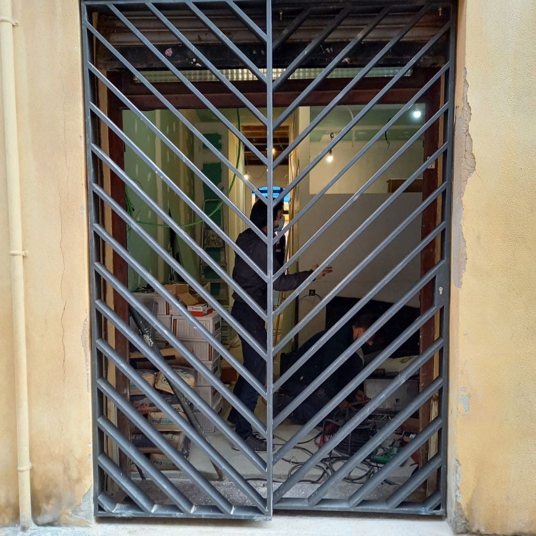 Un hombre está de pie en una habitación detrás de una puerta de metal.