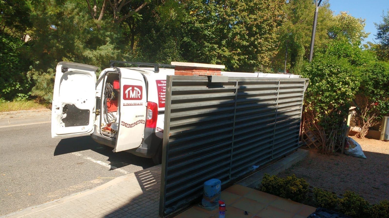 Una camioneta blanca está estacionada al costado de la carretera al lado de una valla.