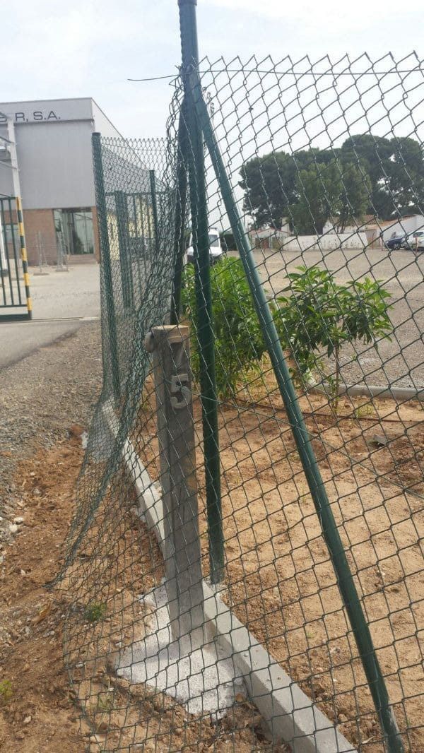 Una valla de alambre con un poste con el número 5 en él.