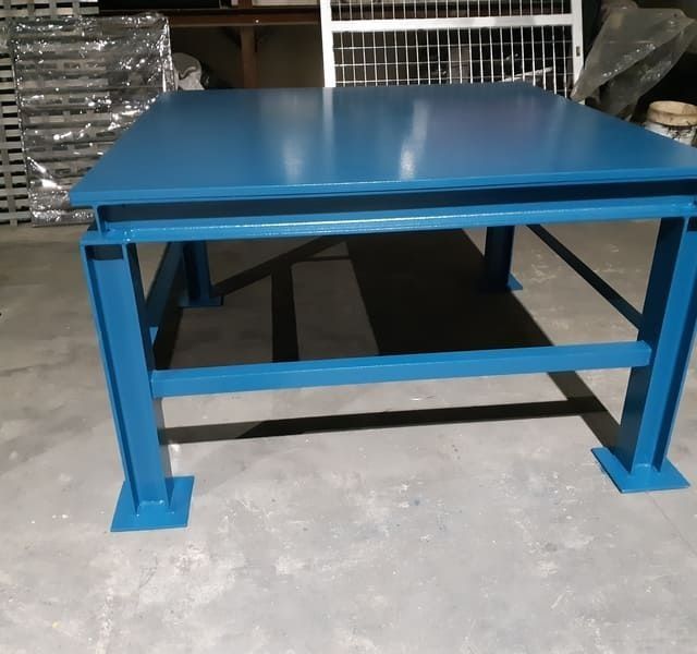 Una mesa azul está colocada sobre un suelo de hormigón.