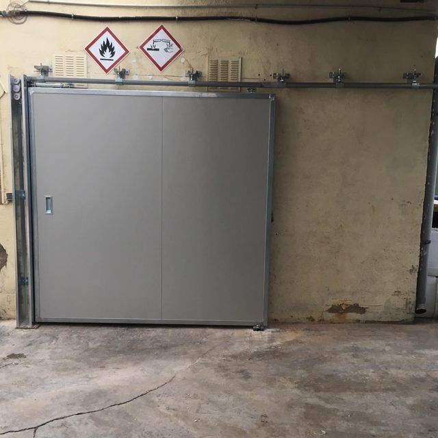 Una puerta corrediza con señales de advertencia en la pared detrás de ella.