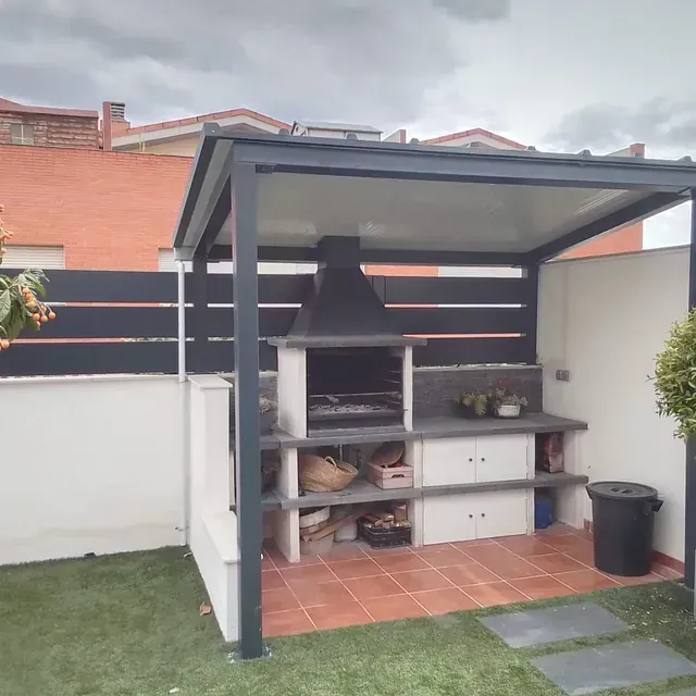 Una barbacoa está situada debajo de una pérgola en un patio trasero.