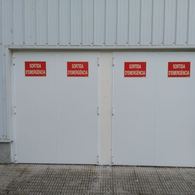 Una puerta de garaje blanca con tres carteles rojos que dicen