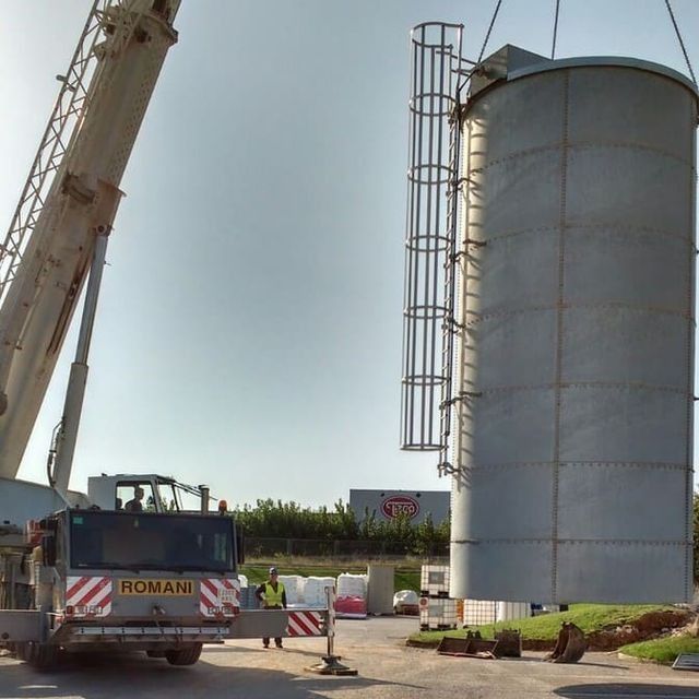 Un camión romano está estacionado frente a un gran silo.