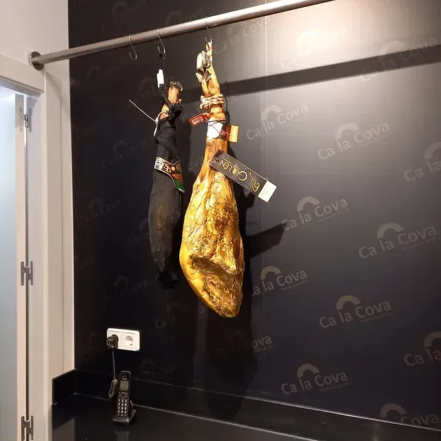 Dos piezas de carne están colgadas en un estante frente a una pared que dice ca la cova