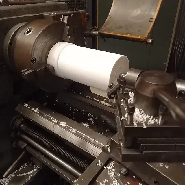 Se está girando un cilindro blanco en un torno.