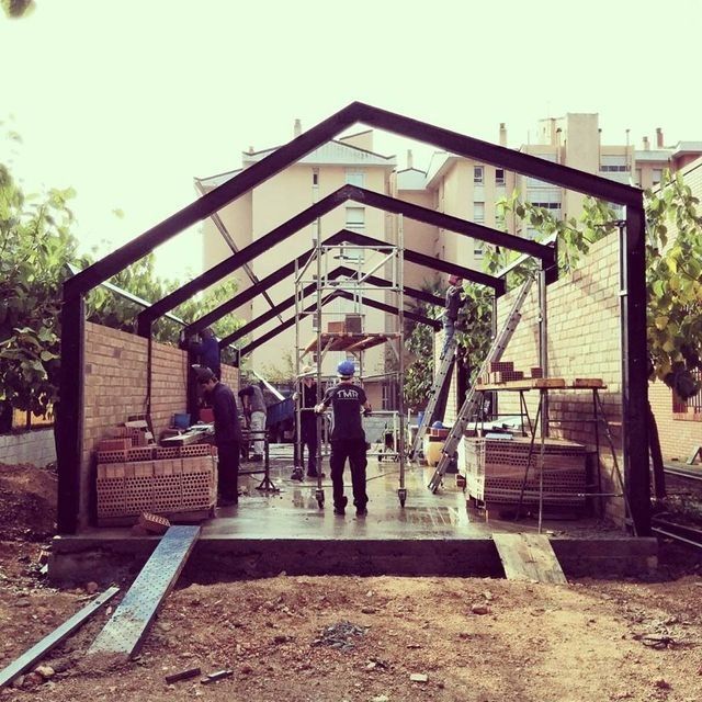 Un hombre que lleva un casco azul está parado frente a un edificio en construcción.