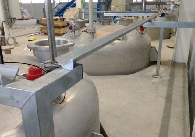 Una barandilla de acero inoxidable en una habitación con muchos tanques.