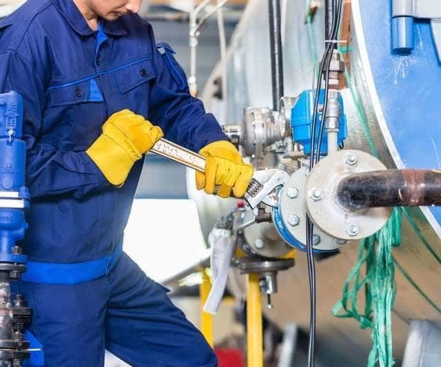 Un hombre está trabajando en una tubería con una llave inglesa.
