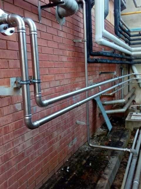 Un montón de tubos están unidos a una pared de ladrillos.