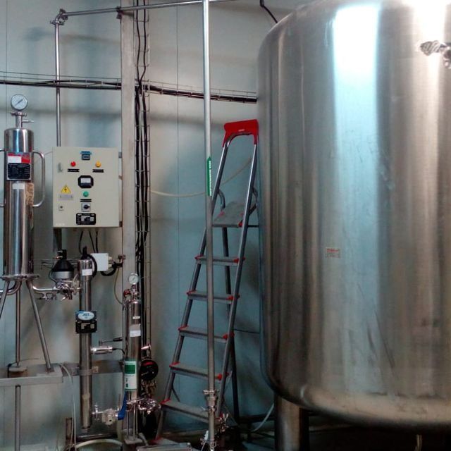 Un gran tanque de acero inoxidable se encuentra junto a una escalera.