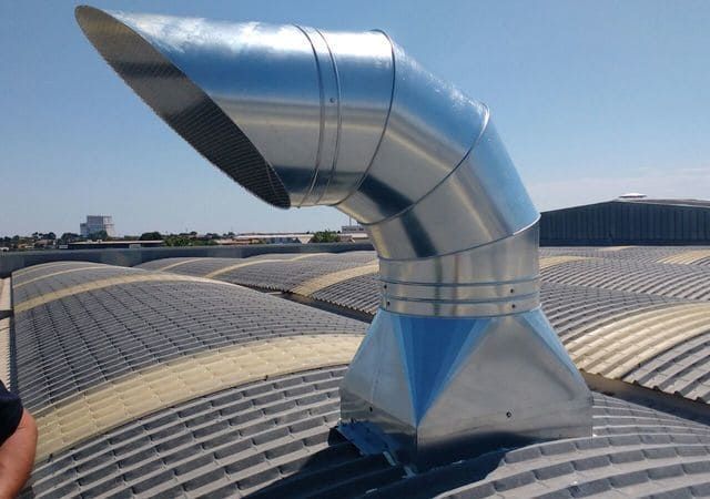 Una persona está mirando una tubería de metal en el techo de un edificio.