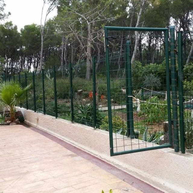 Una valla verde con una puerta que está abierta