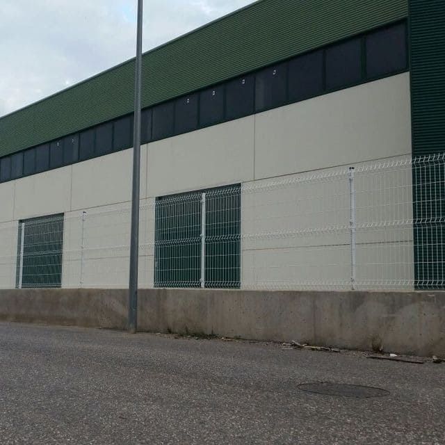 Un edificio verde y blanco con una valla alrededor.