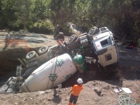 Un camión hormigonera se encuentra tendido de lado en el suelo.