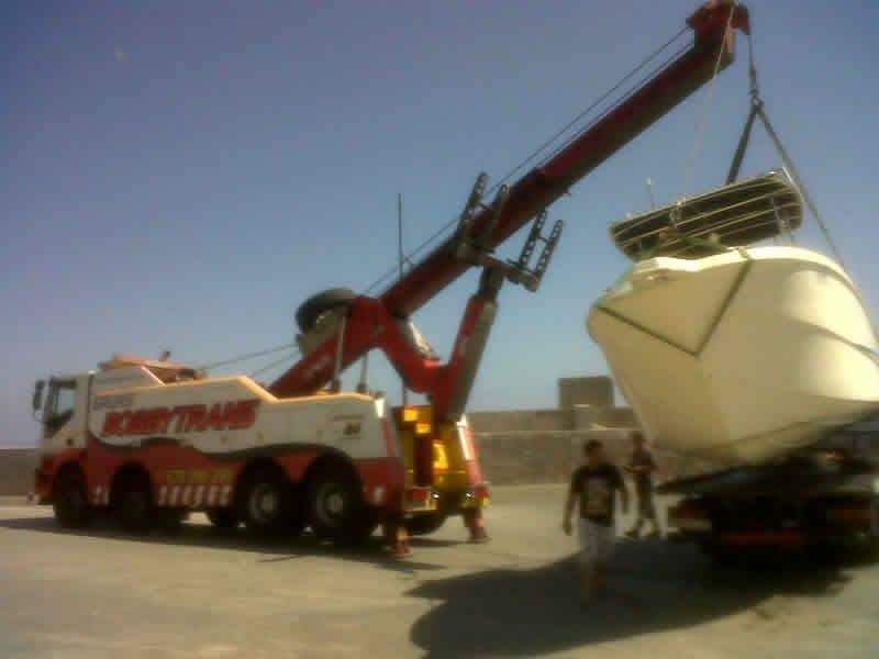 Una grúa roja y blanca está levantando un barco