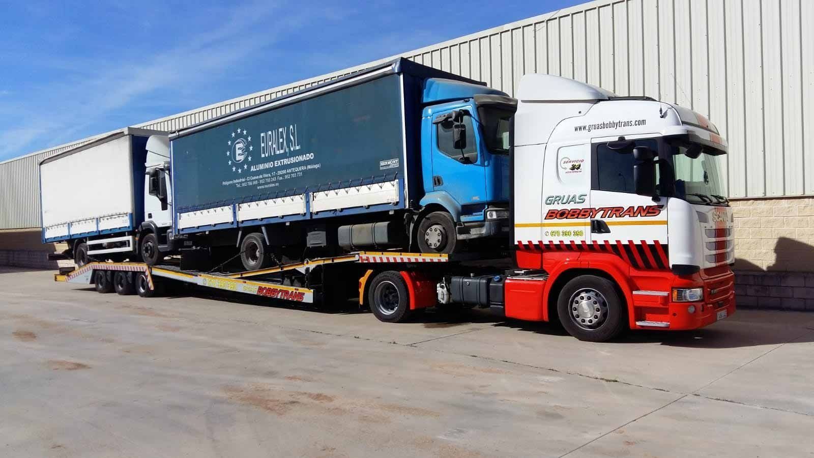 Un camión semirremolque de gran tamaño está estacionado en un estacionamiento al lado de un edificio.