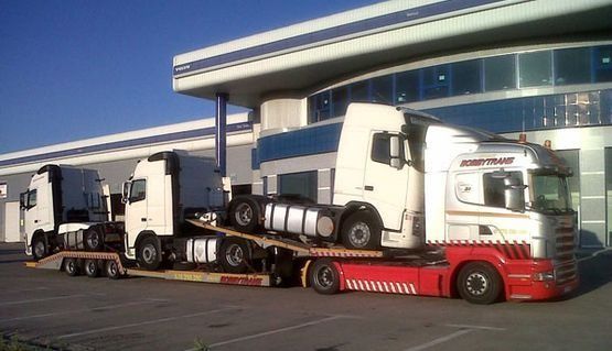 Tres camiones semirremolques están estacionados frente a un edificio.