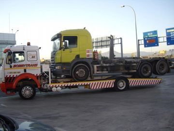 Un camión amarillo está siendo remolcado por una grúa.
