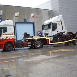Un camión está siendo remolcado por otro camión en un estacionamiento.