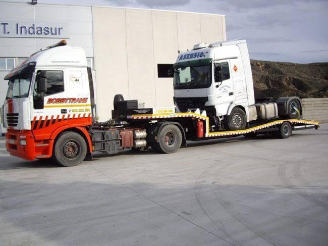 Dos camiones están estacionados frente a un edificio que dice t. indasur
