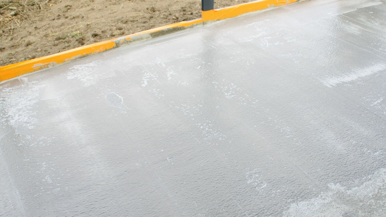 Surface de béton humide avec bordure jaune à gauche.