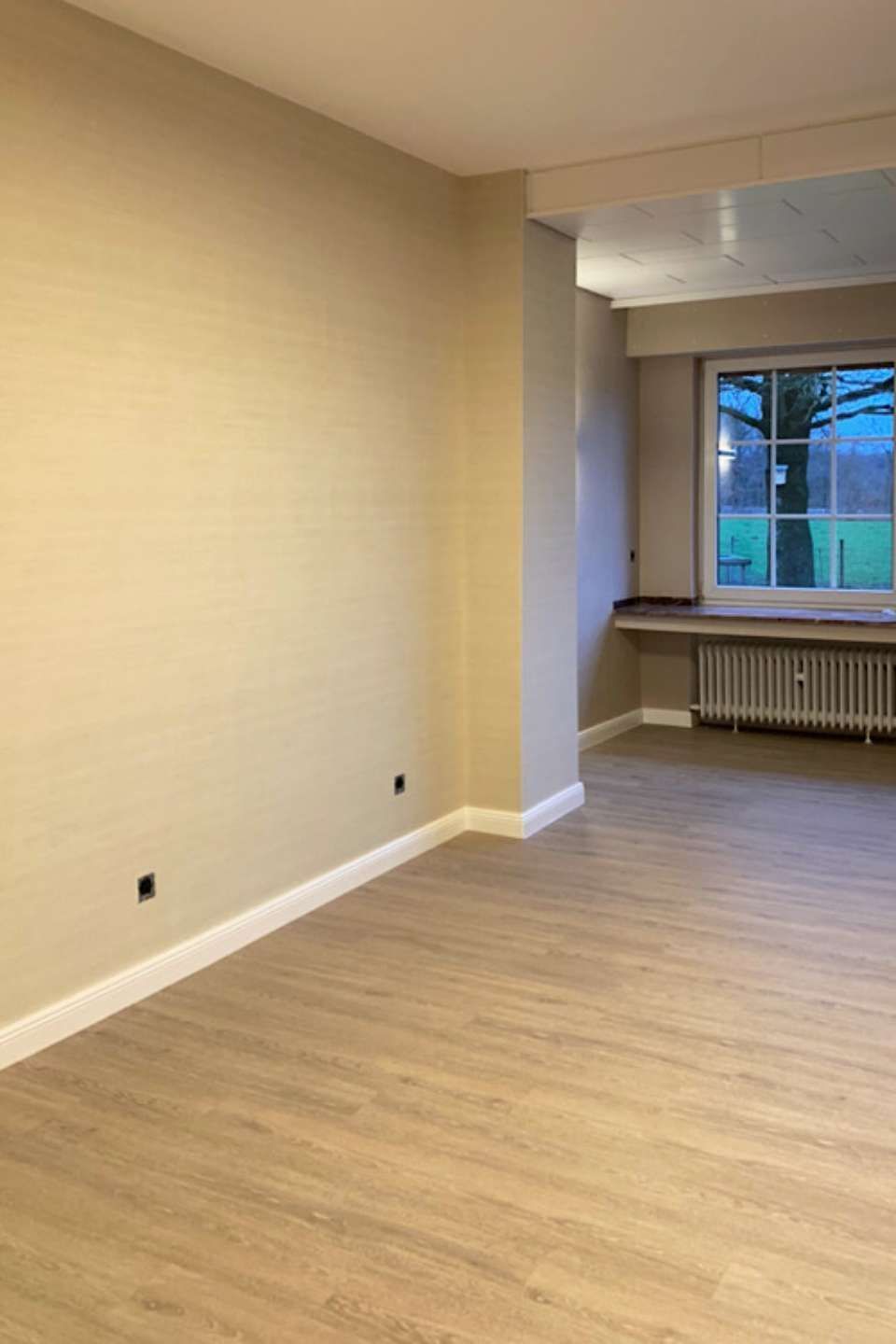 Leerer Flur mit hell-beige gestrichenen Wänden und Holzfußboden