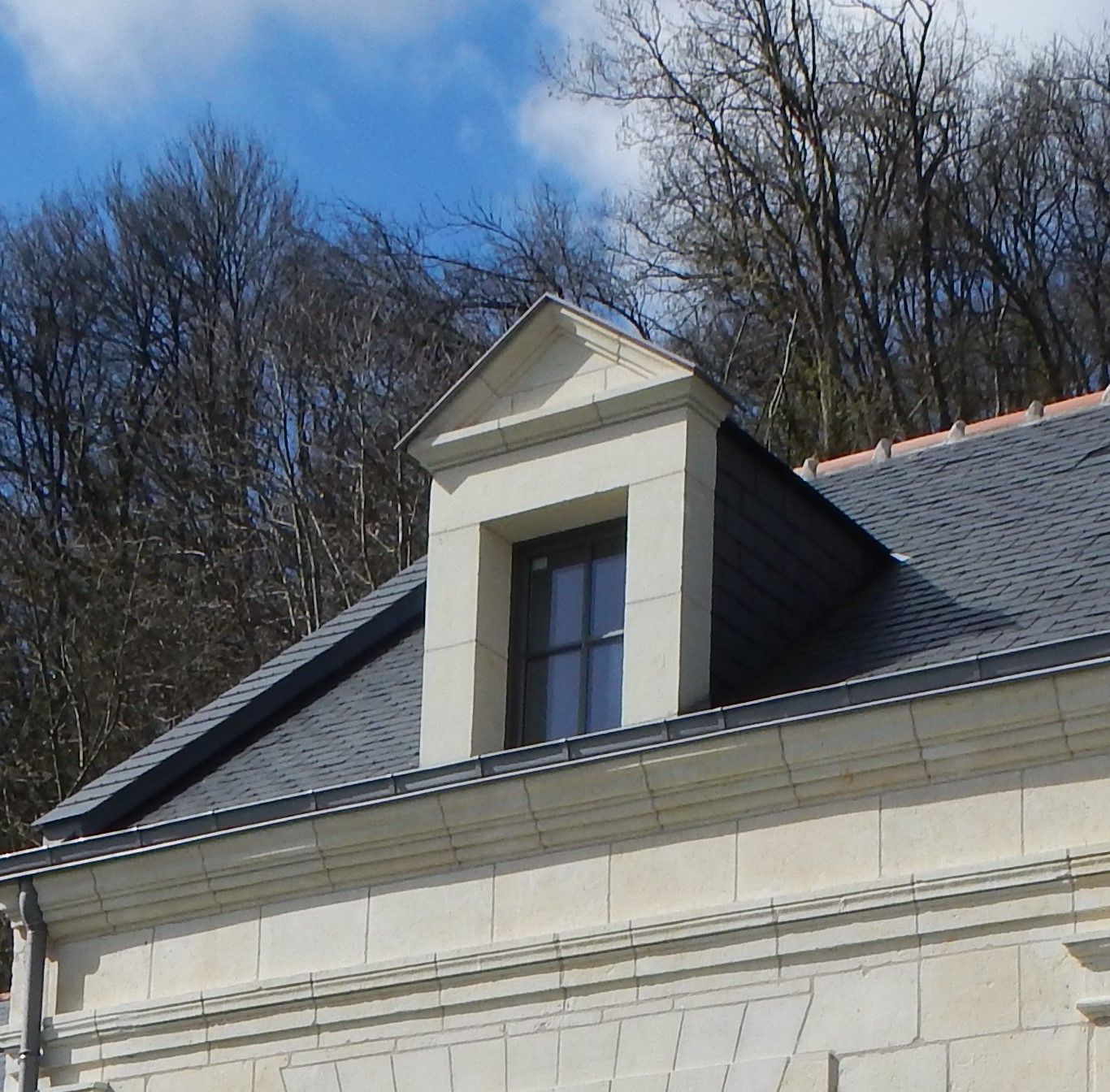Façade de maison après la taille, la pose et le ravalement de façade en tuffeau d'une lucarne 