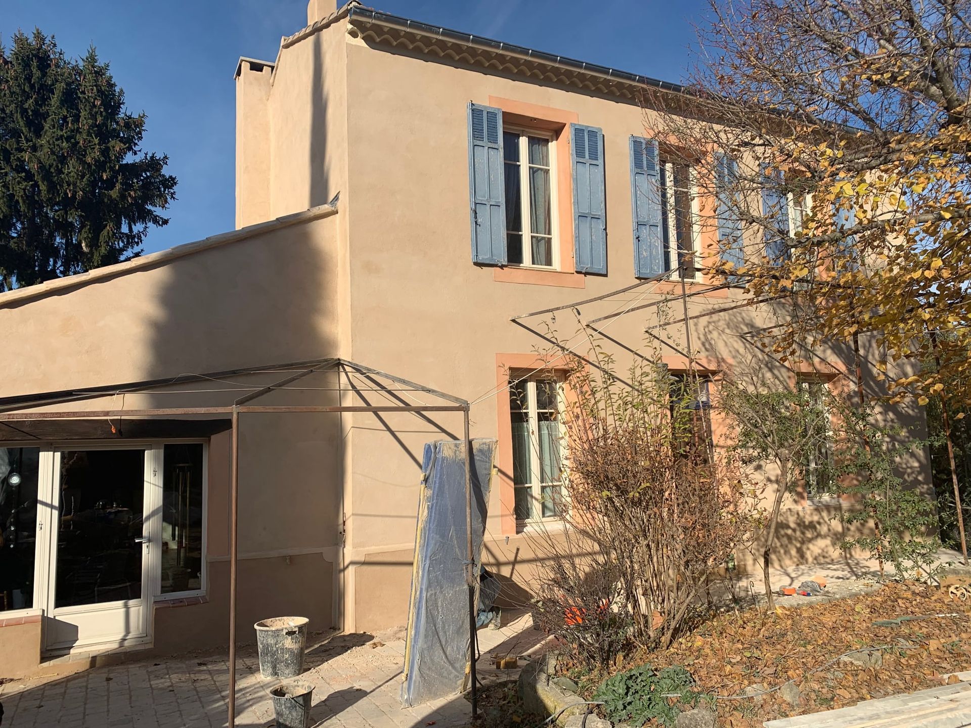 Maison beige avec des volets bleus en bois
