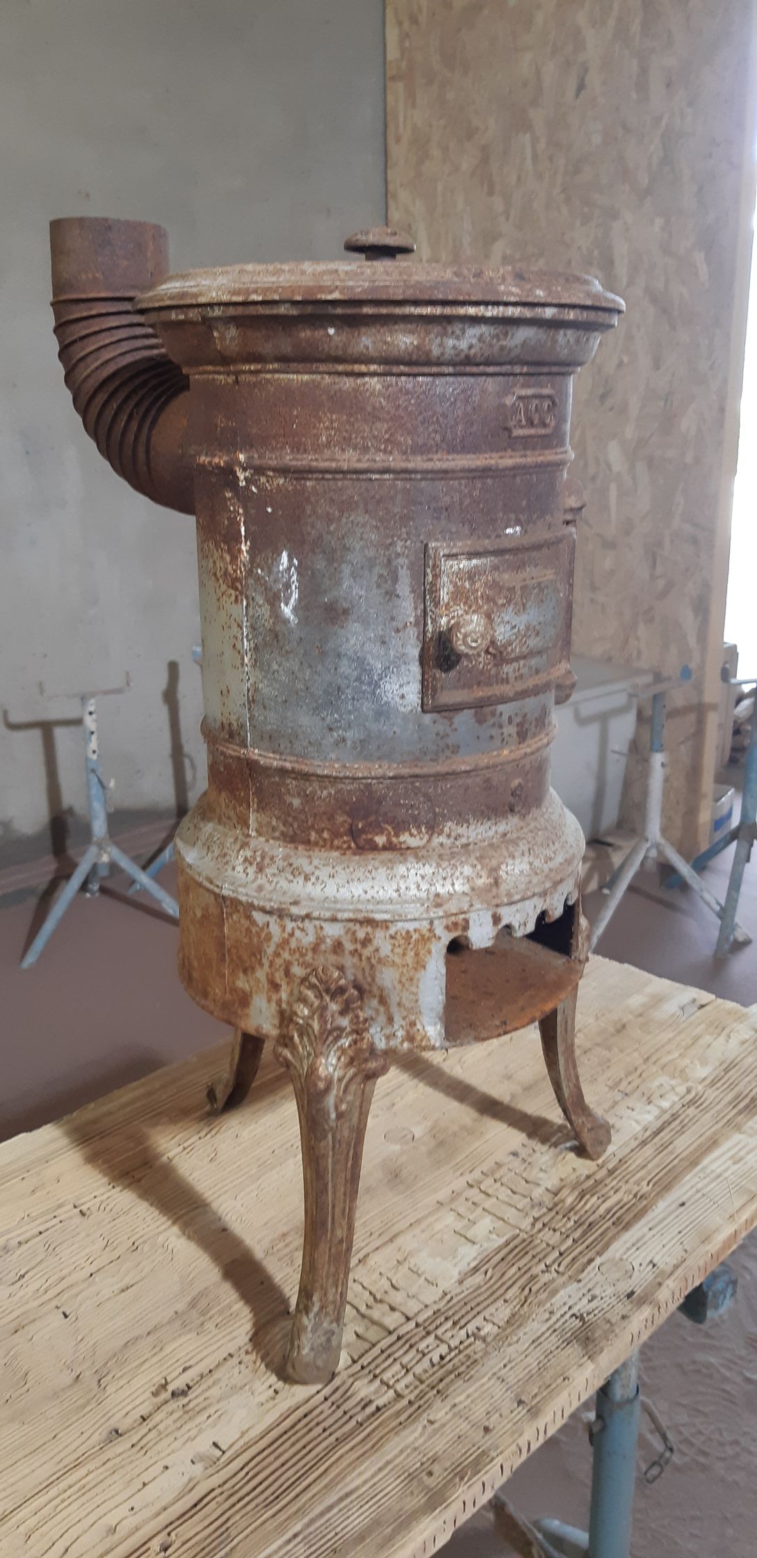Poêle en métal rouillé d'époque posé sur une table en bois contre un mur nu
