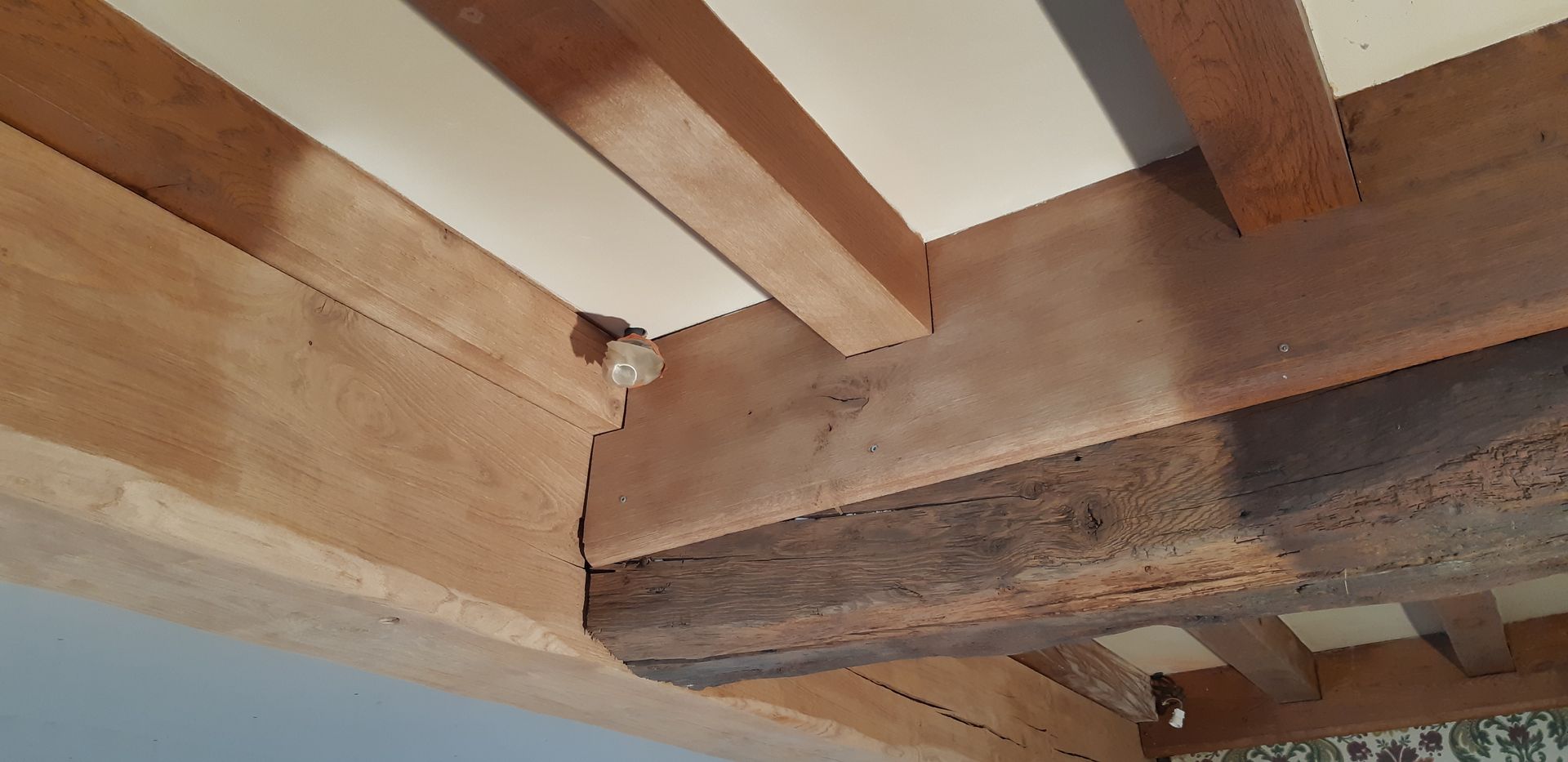 Gros plan sur des poutres en bois au plafond, en cours de décapage par aérogommage