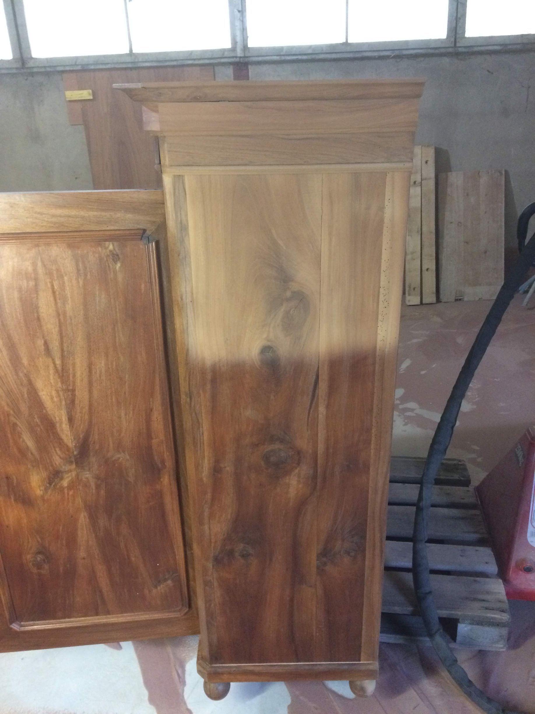 Deux portes ou panneaux d'armoires en bois se trouvent dans un atelier, avec une porte teintée plus foncée devant.