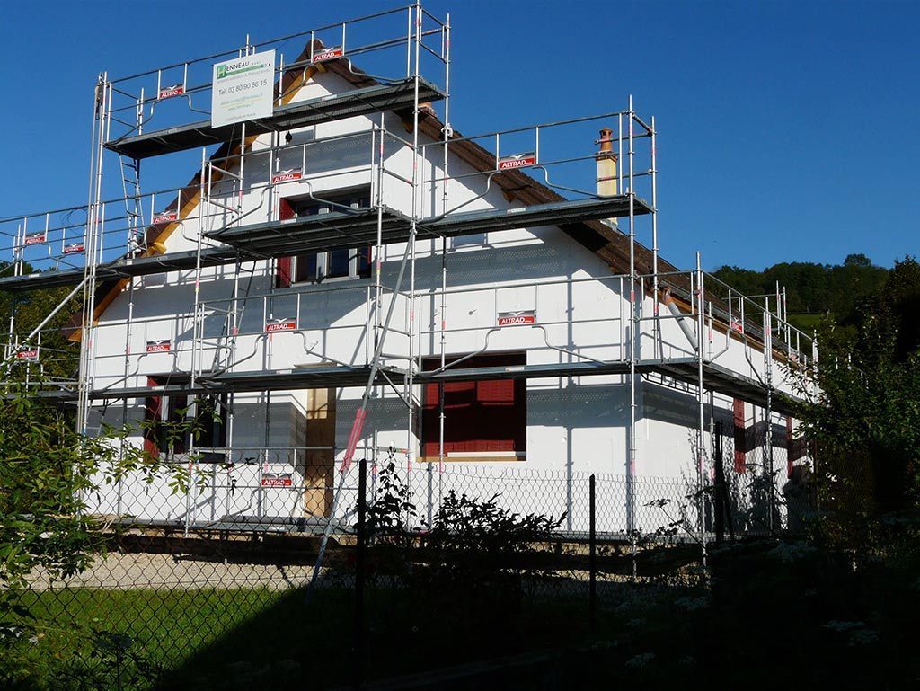 Bâtiment blanc avec échafaudages durant des travaux de rénovation de façade.