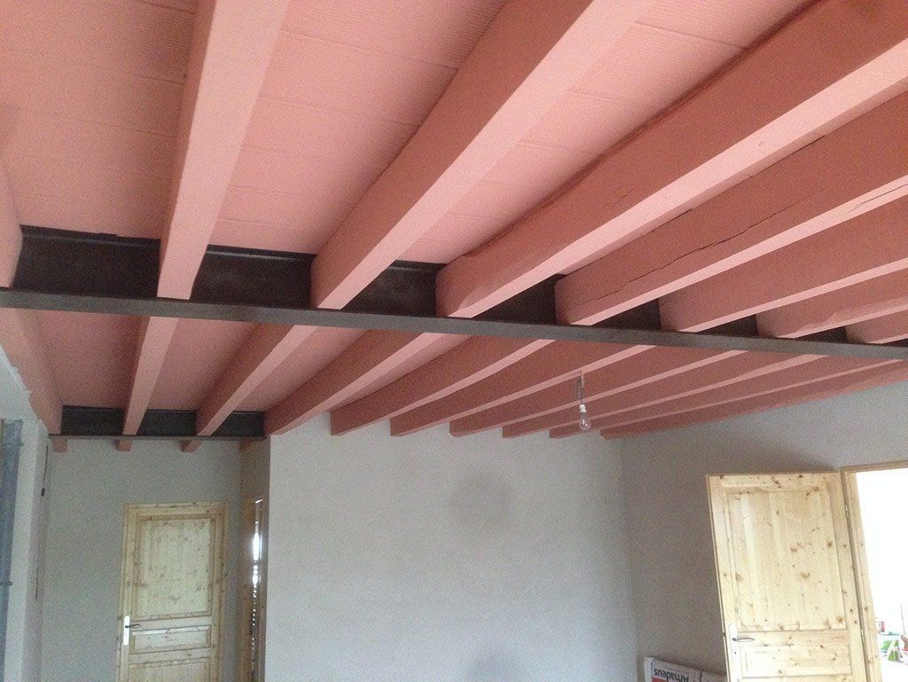 Pièce intérieure avec poutres roses au plafond, murs blancs et deux fenêtres lumineuses