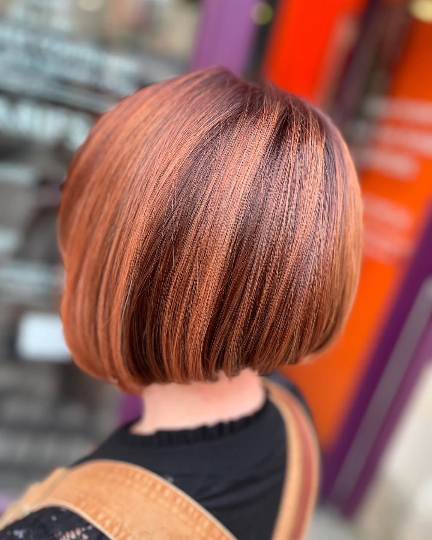 Une personne aux cheveux ondulés d'un rouge et d'un orange éclatants se tient dans un salon décoré de tranches d'orange séchées suspendues avec des cristaux.