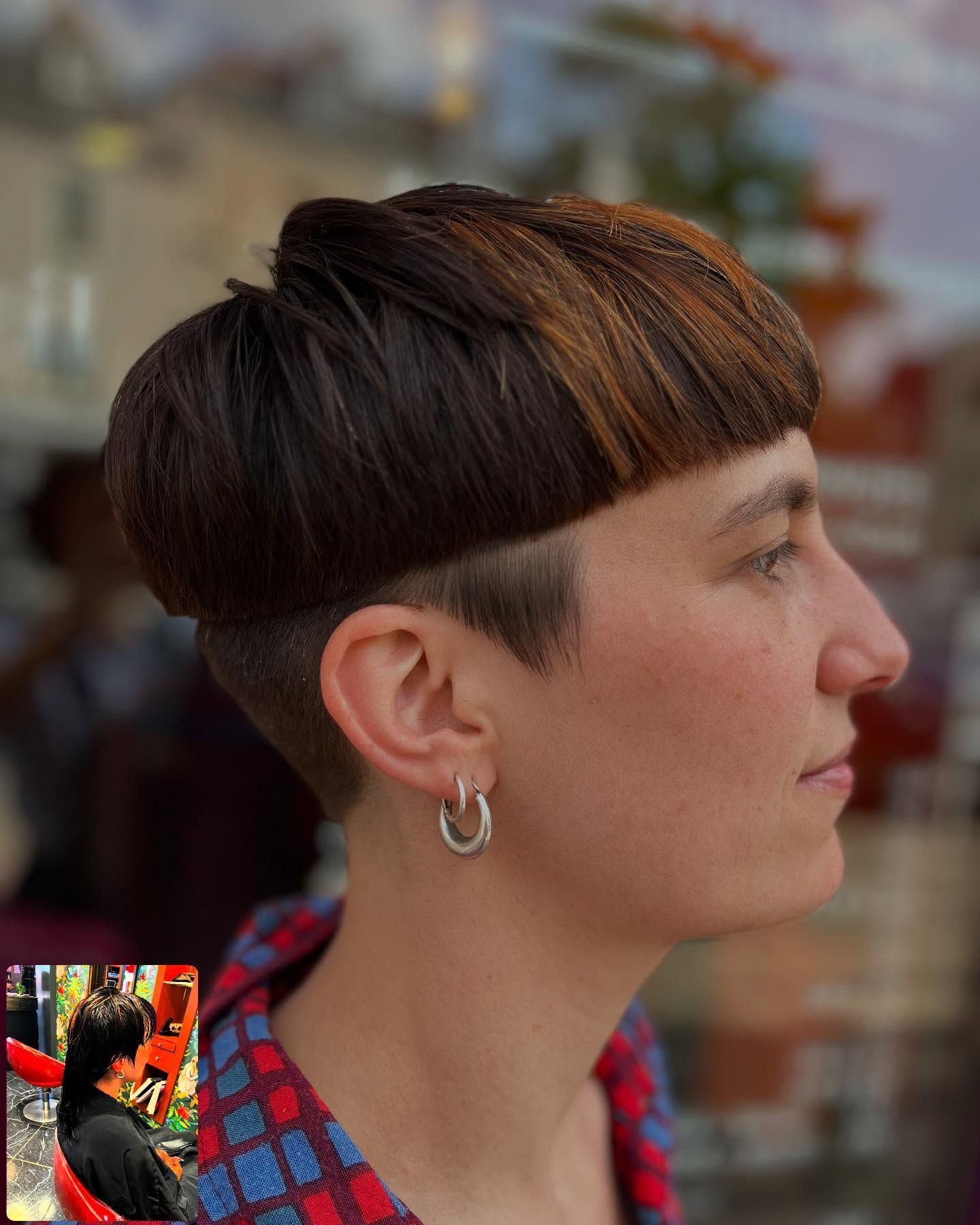 Profil latéral d'une personne avec une coupe au bol courte bicolore et une nuque dégagée, portant de petites boucles d'oreilles créoles en argent.