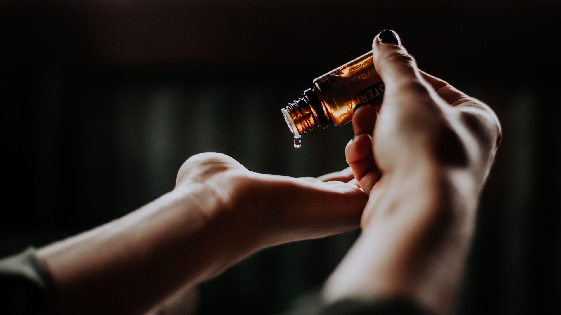 Eine Frau gießt ätherisches Öl in ihre Hand.