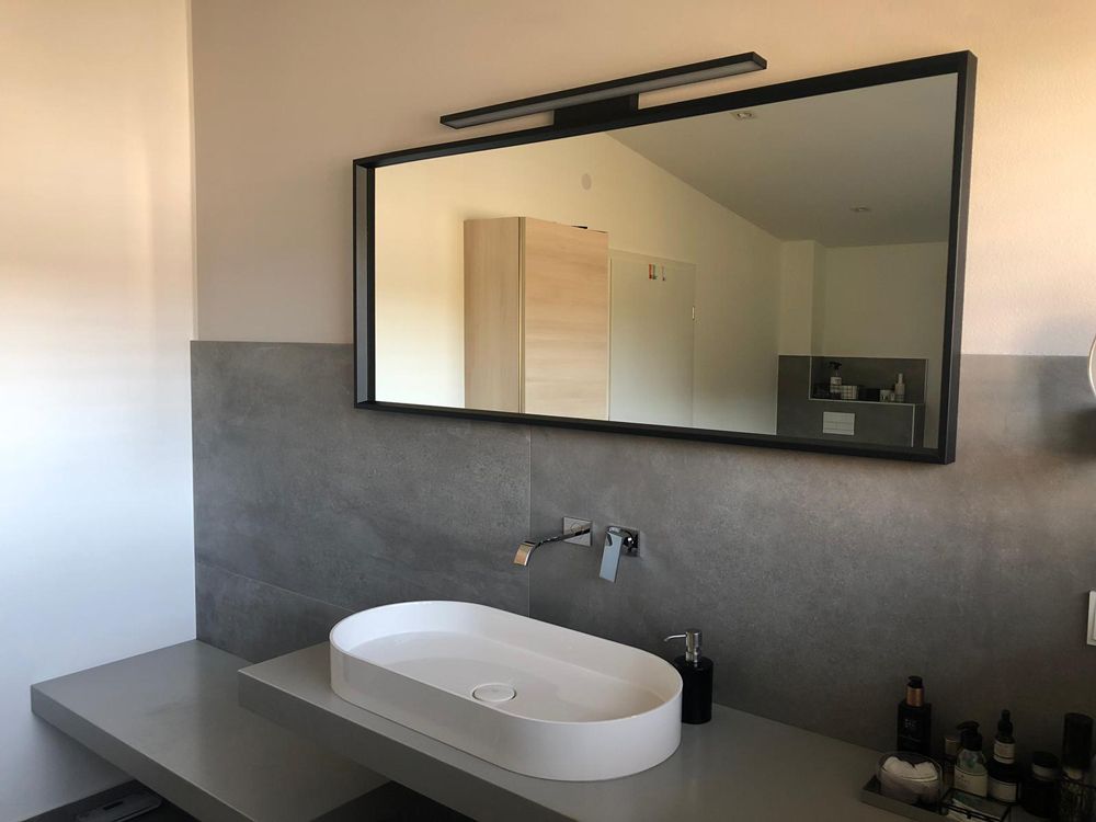 Moderner Badezimmerwaschtisch mit ovalem Waschbecken, großem Spiegel und grauer Steinrückwand