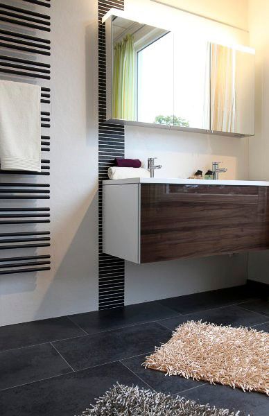 Moderner Badezimmerschrank mit Spiegelschrank, gestreifter Wand, dunklem Fliesenboden und Hochflorteppich