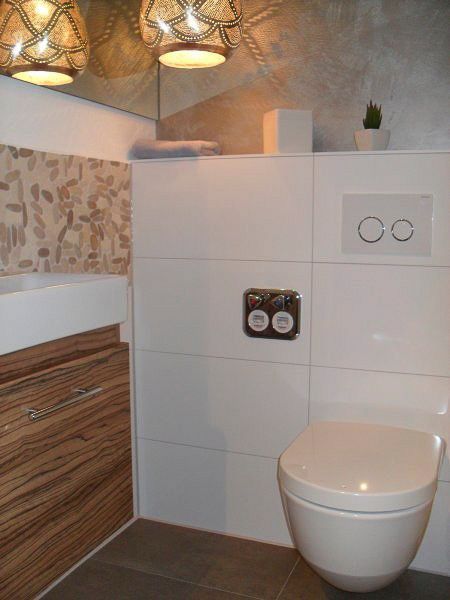 Modernes Badezimmer mit weißen Fliesen, Waschtisch aus Holz, Toilette und dekorativer Deckenbeleuchtung