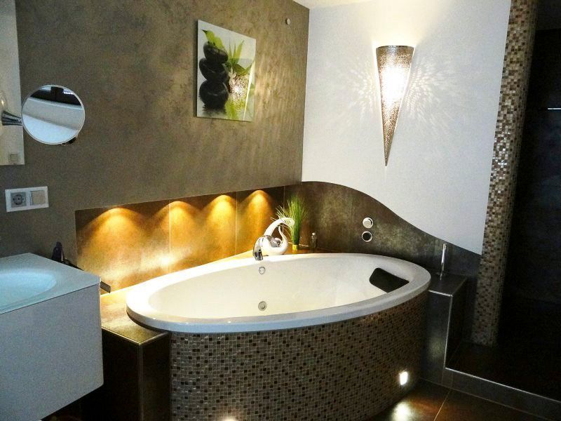 Modernes Badezimmer mit runder weißer Badewanne, Wandleuchten und strukturierten braun-weißen Wänden