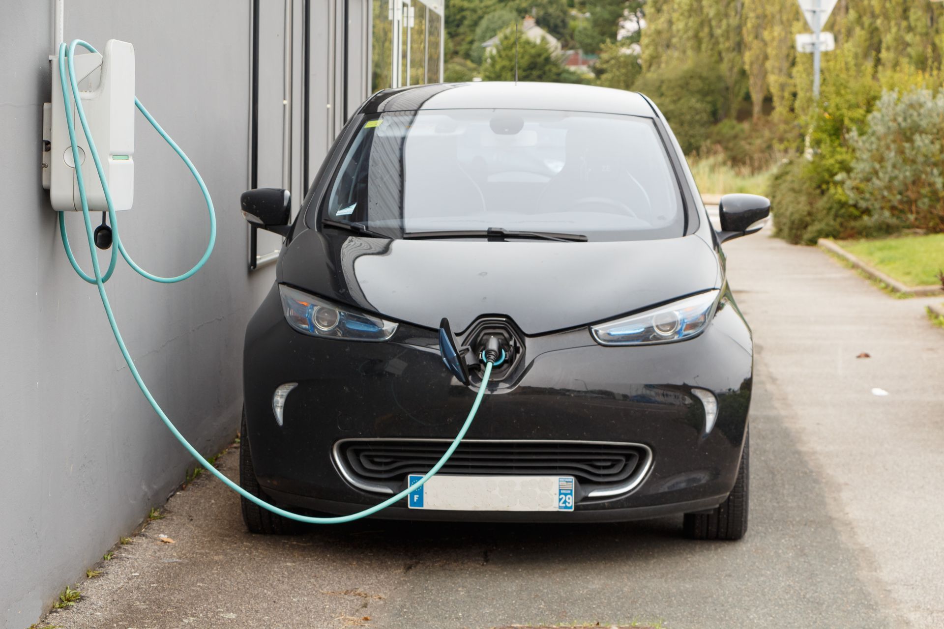 Voiture électrique en charge à une borne murale à côté d'un bâtiment.