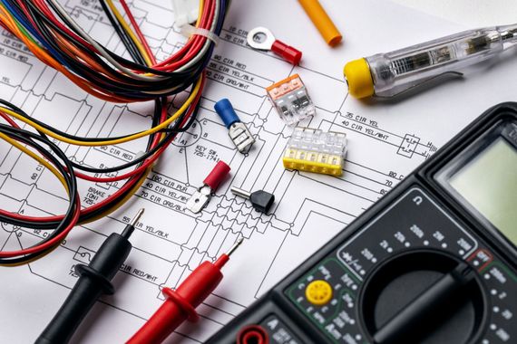 Multimètre, fils, résistances et tournevis sur un schéma électronique.