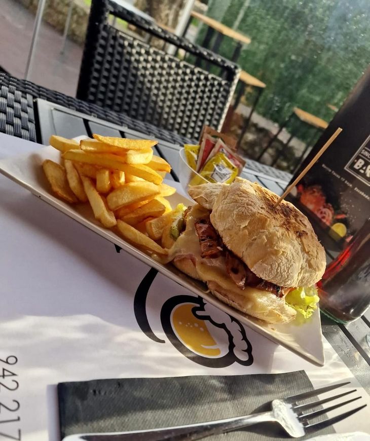 Un plato de comida con una hamburguesa y papas fritas en una mesa.