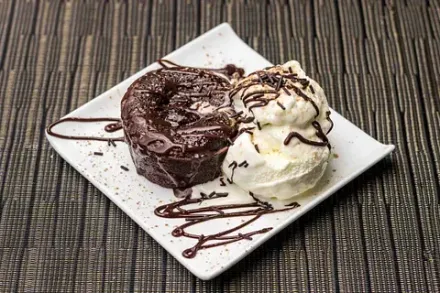 Un pastel de lava de chocolate con helado en un plato blanco.