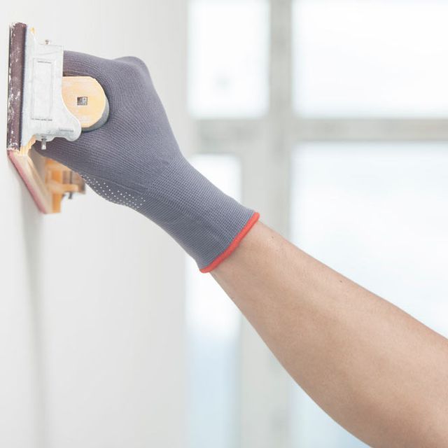 Una persona que lleva un guante está enyesando una pared